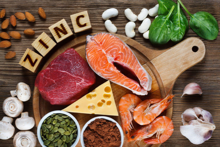 Foods High in Zinc as salmon, seafood-shrimps, beef, yellow cheese, spinach, mushrooms, cocoa, pumpkin seeds, garlic, bean and almonds. Top view