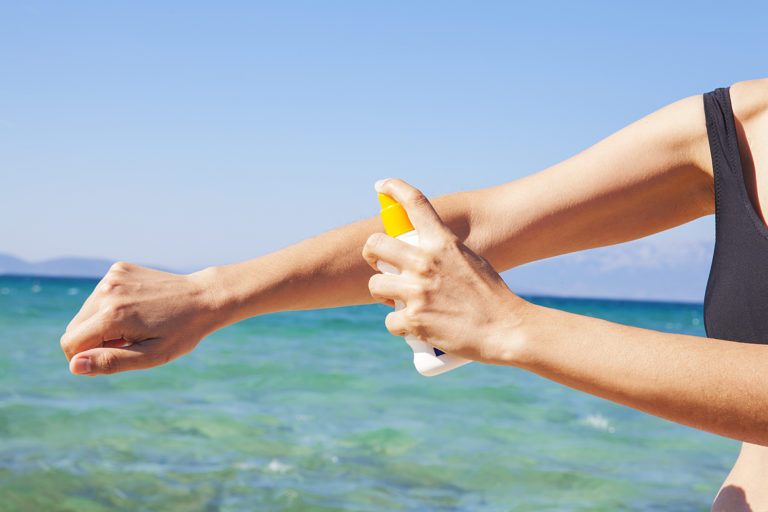 Mujer en la playa poniéndose protección solar en la piel