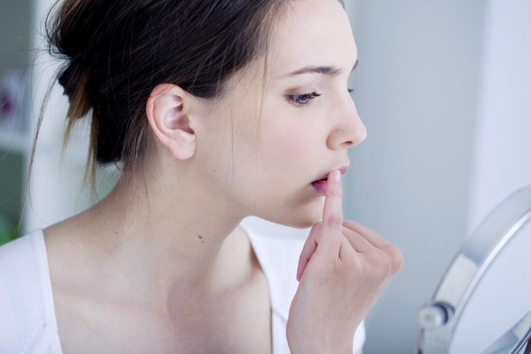 Woman looking her herpes at the mirror