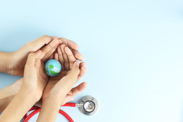 World health day concept - Top view hands hold blue earth on blue background with stethoscope